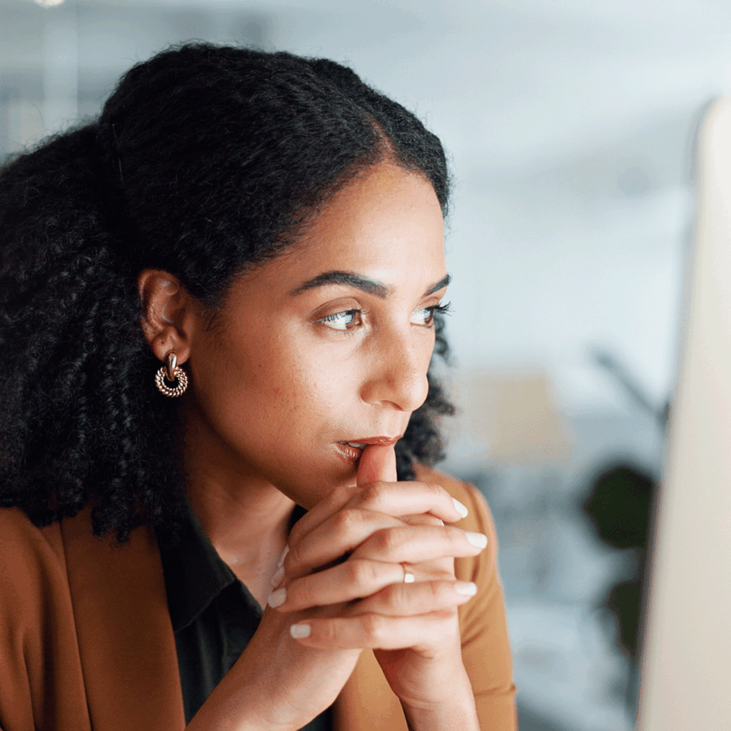 Frau mit nachdenklicher Miene vor einem Computer, bereit für Bewerbungsgespräch
