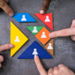 Das Bild zeigt eine Illustration mit unterschiedlichen Puzzleteilen und vier Finget, die diese zusammenschieben