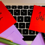 Rote Klebezettel mit der Aufschrift ‚Job‘ auf einer Laptop-Tastatur als Symbolbild für das Thema Job posten