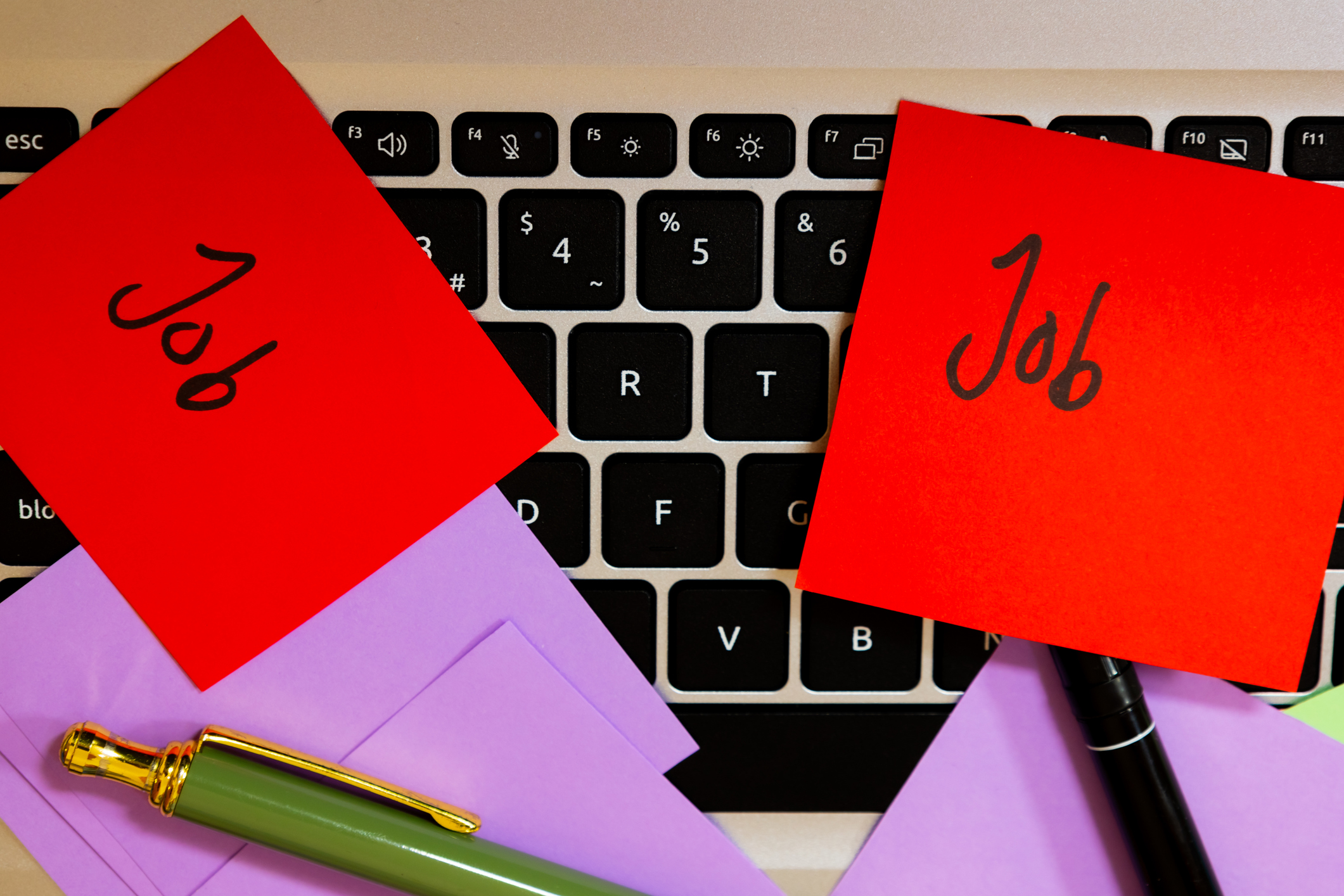 Rote Klebezettel mit der Aufschrift ‚Job‘ auf einer Laptop-Tastatur als Symbolbild für das Thema Job posten